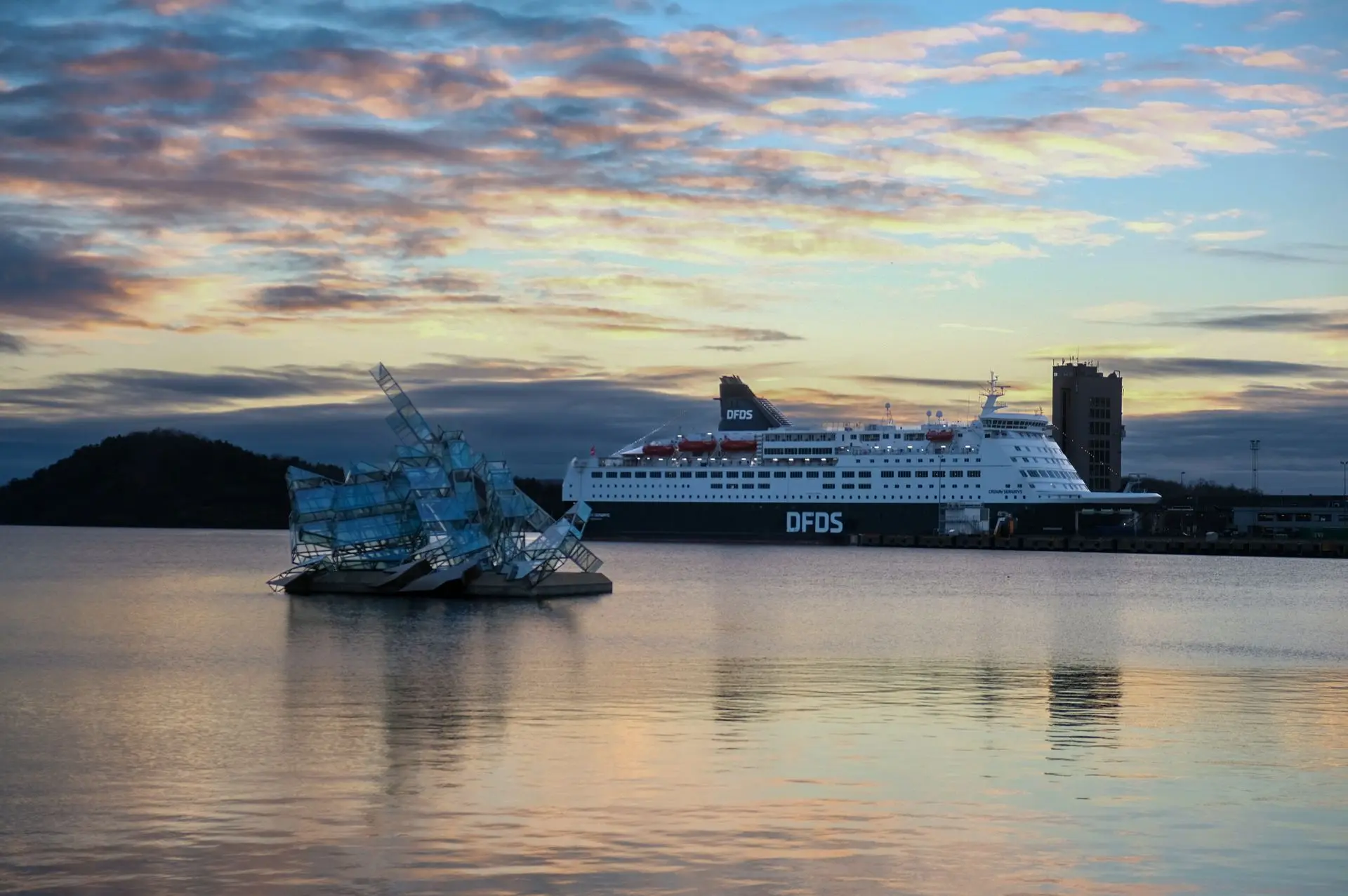 A view of Oslo’s harbor at dusk, where a modern glass sculpture floats on the water alongside a DFDS ferry. The soft reflections and layered composition create a sense of stillness and depth. Captured by Louis Mas, photographer and videographer, this image highlights the blend of urban design and natural beauty in the Norwegian capital.